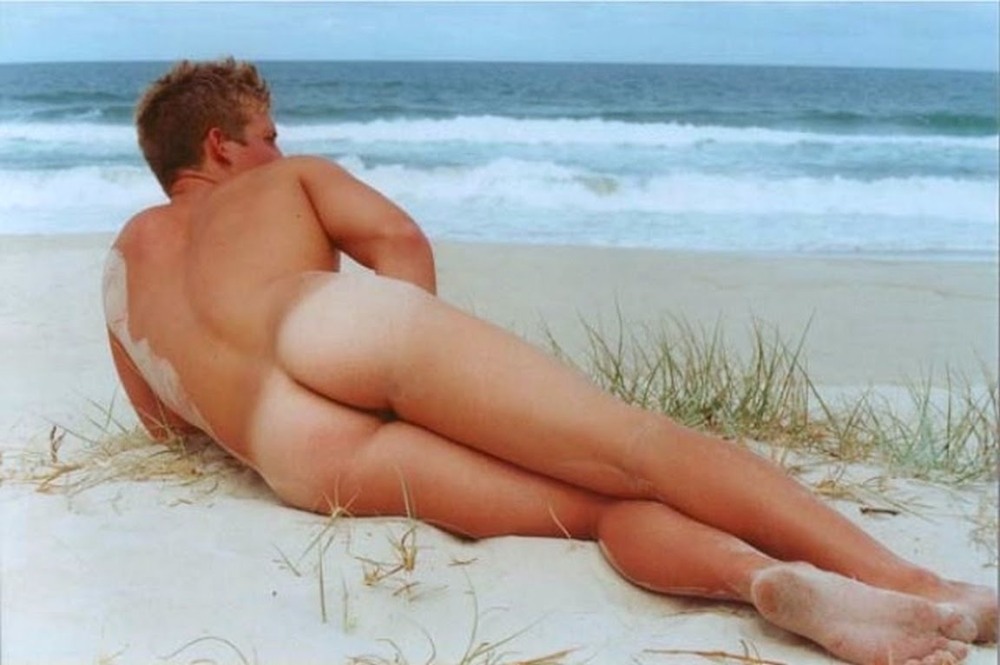 A naked man lies on the beach