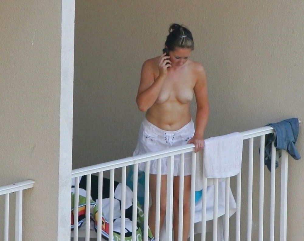 A naked woman sunbathes on the balcony